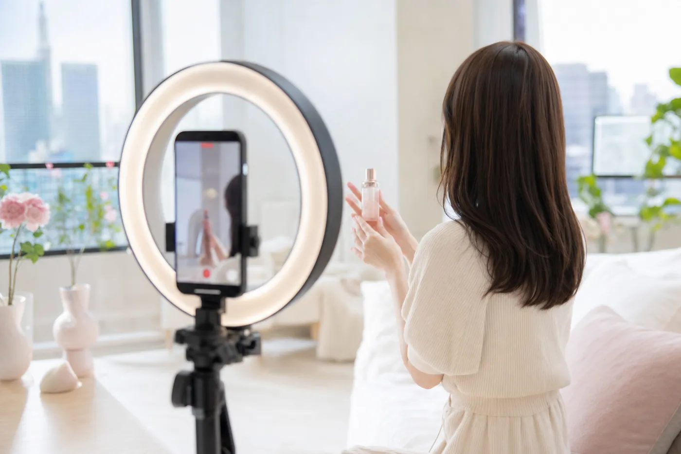 TikTok・Instagram広告の縦動画撮影の様子。リングライトとスマホ三脚の前で商品を手にする出演モデル